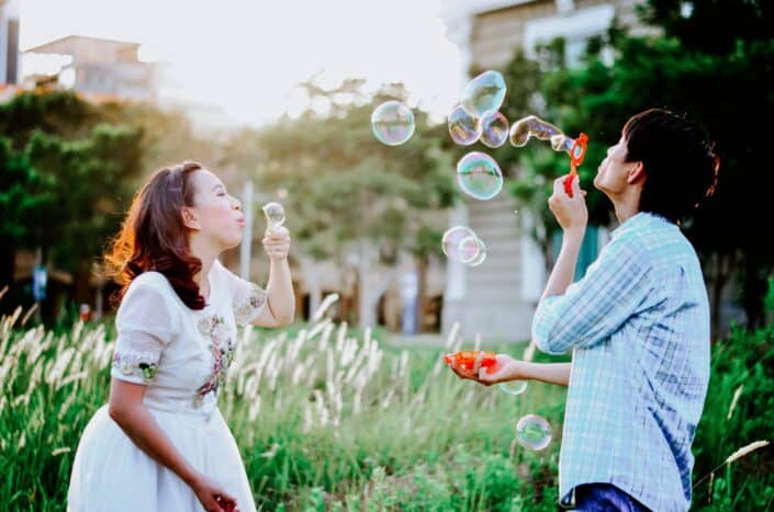 mana nd woman blowing bubbles outdoors