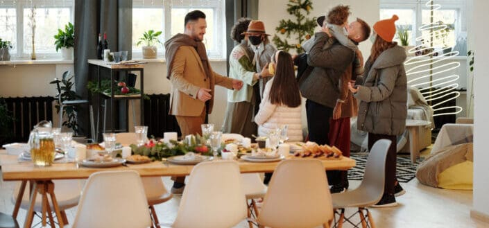 a group of people greeting each other by a dining table