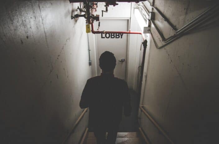 a man walking down a flight of stairs to a lobby
