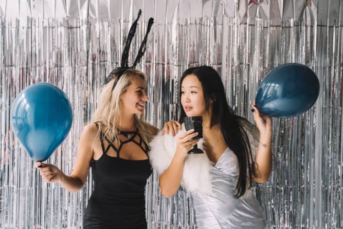 two women holding balloons in a festive setting