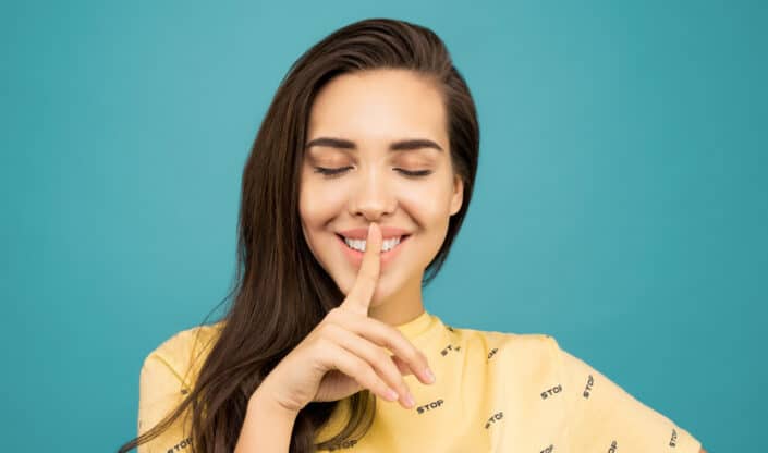 a woman with her eyes closed and her finger to her lips