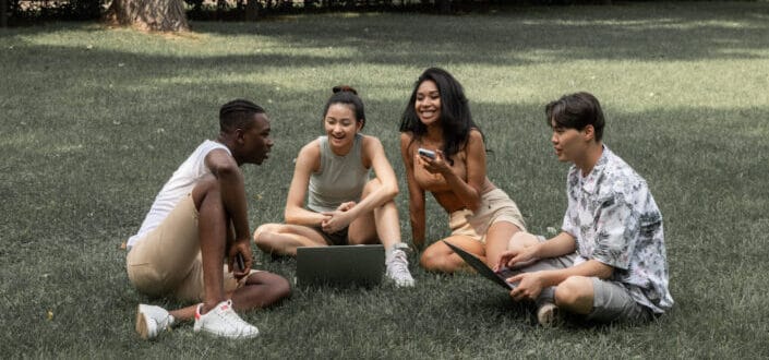group of four friends smiling on the grass