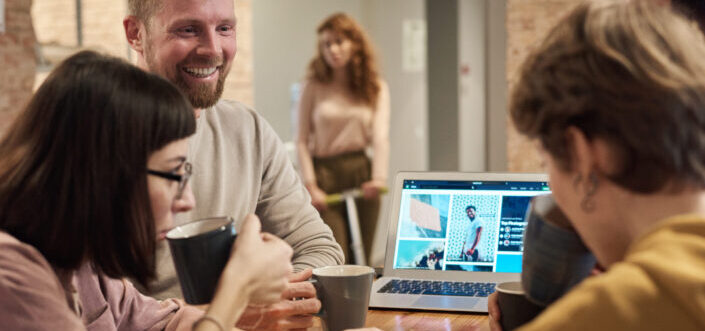 smiling guy presenting to couple sipping coffee