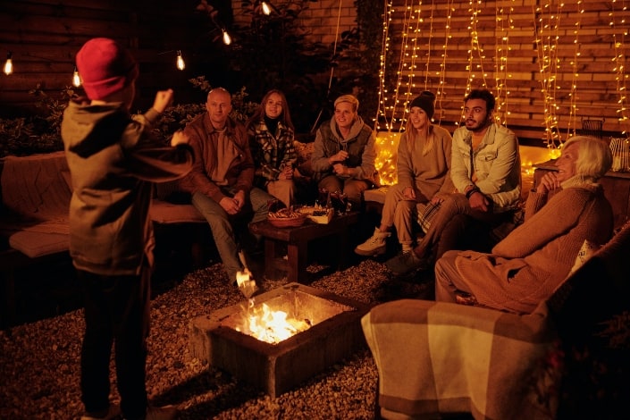 group of adults playing charades around a firepit