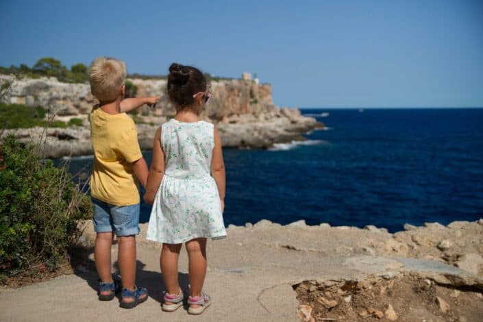 boy and girl holding hands over a cliff