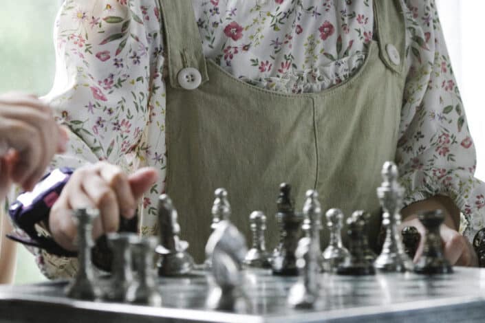 Focused kids playing chess with grandmother