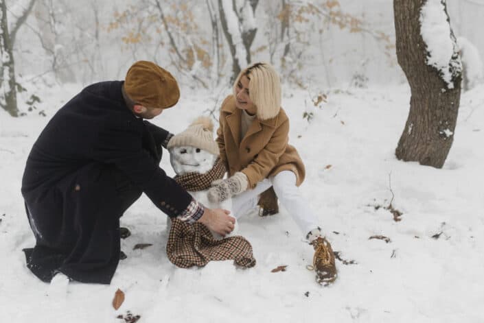 two people building a snowman 