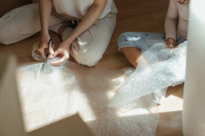girls cutting bubble wrap on floor
