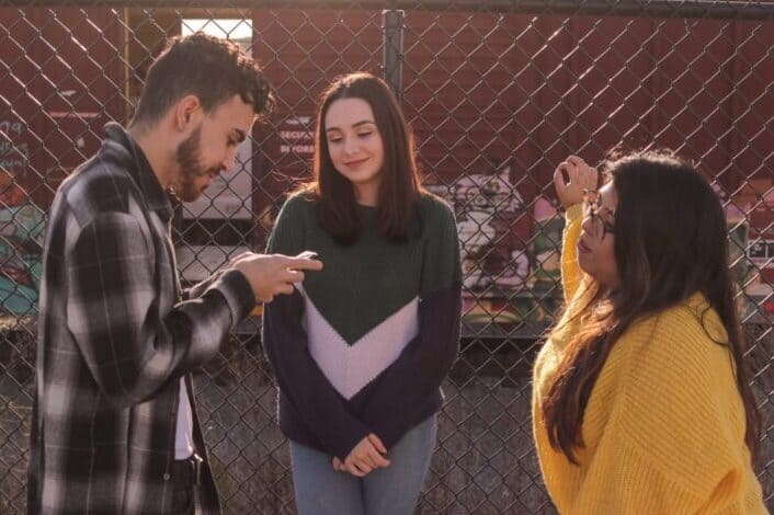 two women and one man standing near fence