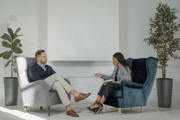 Two people talking while sitting on chairs