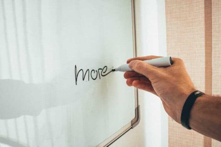 Person writing "more" on the board