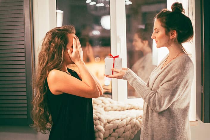 woman surprising her friend with a gift