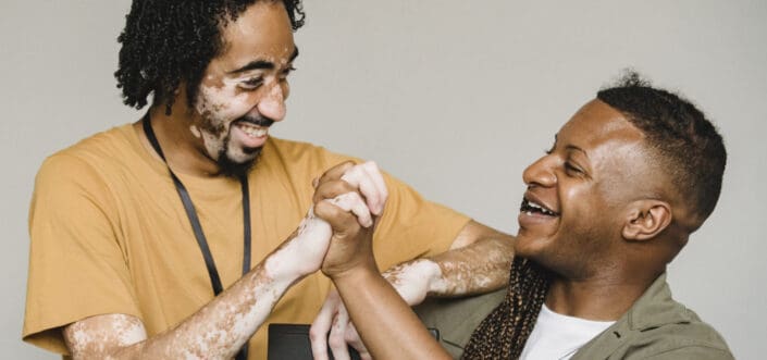 Friends holding hands while smiling at each other.