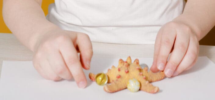 Kid playing marbles with his starfish toy