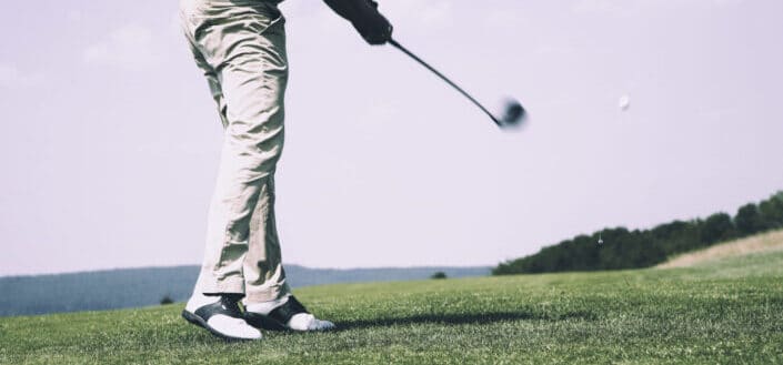 Man playing golf outside under a sunny weather