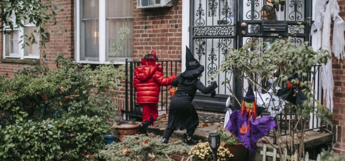 Unrecognizable little girls in costume trick or treating on halloween
