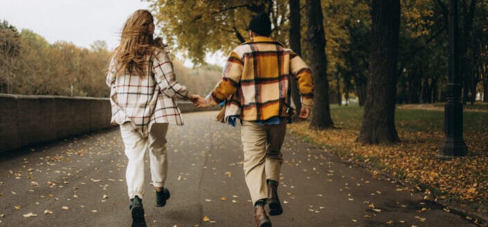 Woman in orange and white jacket walking on road