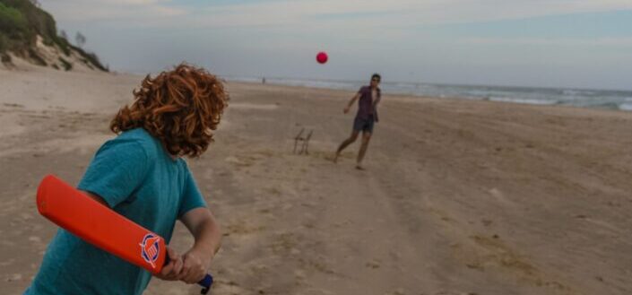 Two friends playing baseball by the beach