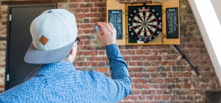 Man in Blue Dress Playing Darts