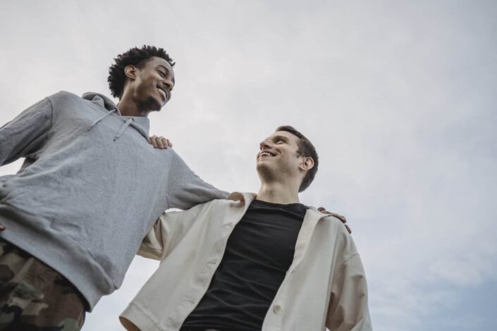 Male Friends Side Hugging Against Cloudy Sky