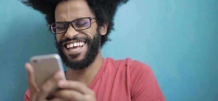 Man in a Shirt Laughing at His Phone