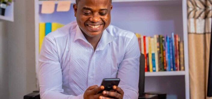 Man in White Long Sleeve Shirt Using a Cellphone