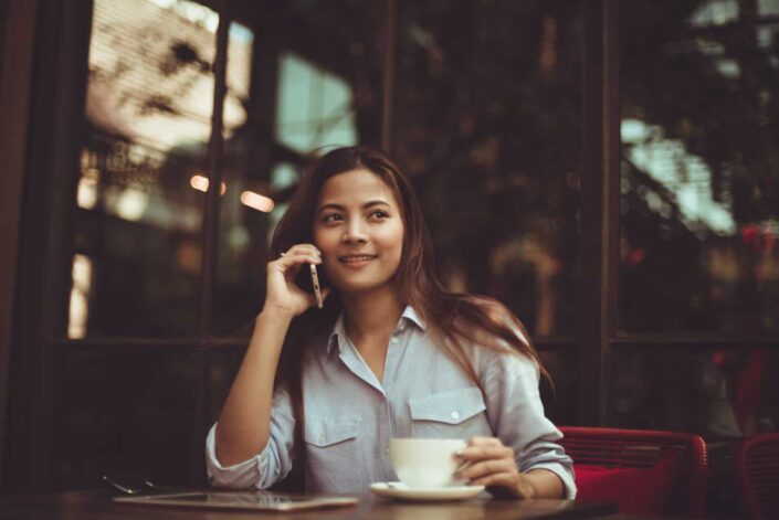 Young Woman Using Mobile Phone in Cafe