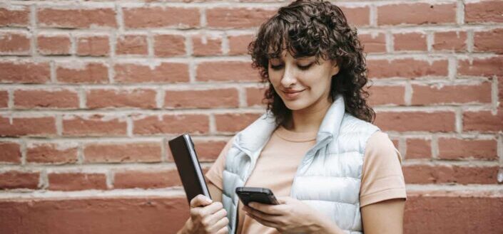 Woman With Laptop Chatting on Her Smartphone