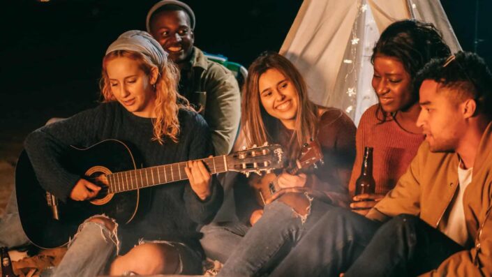 Friends Singing While Sitting on Beach Sand