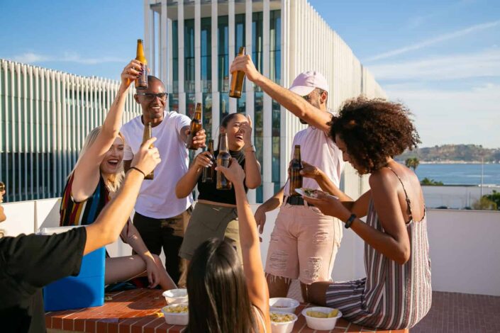 Friends Toasting With Beer Bottles on Rooftop