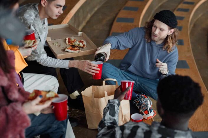 Man in Hoodie Pouring Wine For His Friend